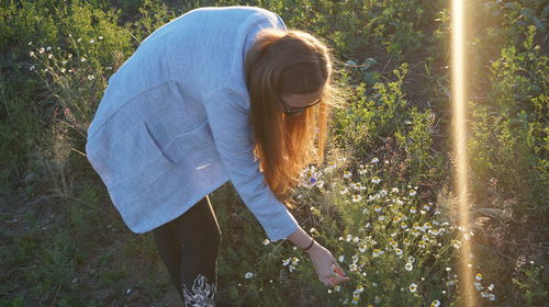 Side view of woman touching while standing by flowering plants