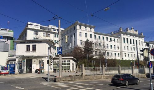 Cars on road by buildings against blue sky