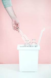 Close-up of woman hand on pink table against wall