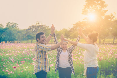 People standing by plants on field against sky