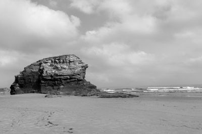Rock formation on beach against sky