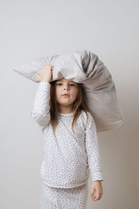 Portrait of cute girl holding pillow on head