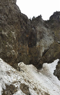 Low angle view of rock formation against sky during winter