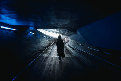 Rear view of woman walking in subway tunnel