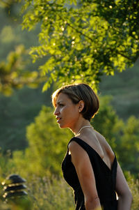 Side view of woman standing against tree