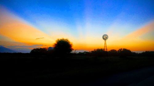 Silhouette trees on field against sky during sunset