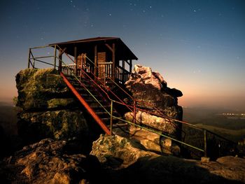 Autumn full moon foggy night. wooden cabin on main peak of rock as view point, dark stars sky