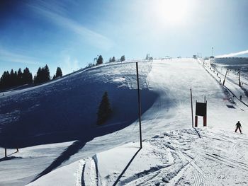 Snow covered landscape against sky on sunny day