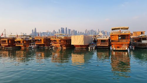 Sailboats moored on river in city against sky