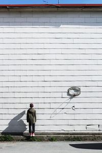 Rear view of boy standing against white wall