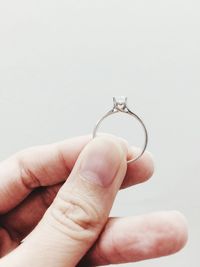 Cropped hand holding ring against white background