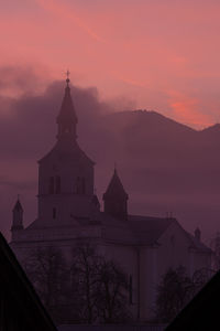 Church by building against sky at dusk