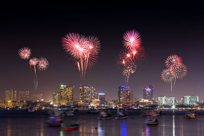 Firework display in city against sky at night