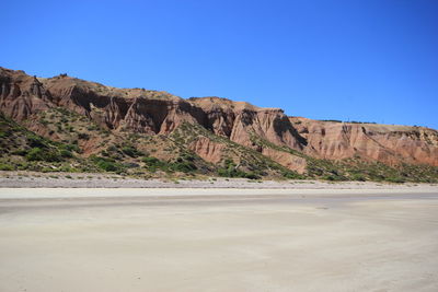 View of calm beach against rocky mountains