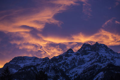 Scenic view of snow covered mountains against sky at sunset