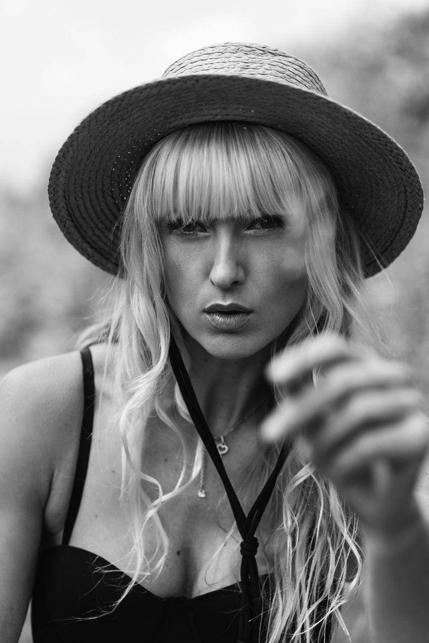 one person, adult, portrait, women, hat, clothing, young adult, black and white, black, white, blond hair, hairstyle, sun hat, long hair, monochrome photography, human hair, fashion, monochrome, fashion accessory, front view, person, female, fedora, looking at camera, headshot, portrait photography, human face, lifestyles, nature, serious, outdoors, casual clothing, waist up, summer, looking
