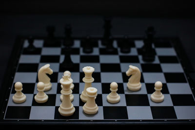 High angle view of chess pieces on board against black background