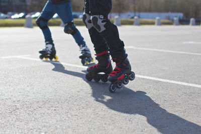 Low section of friends roller skating on road