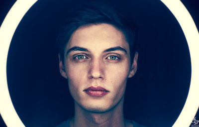 Portrait of young man against black background