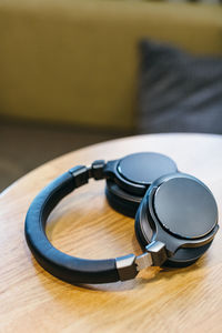 Photo of black wireless headphones on wooden table. high-quality expensive headphone.