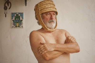 Portrait of shirtless man standing against wall