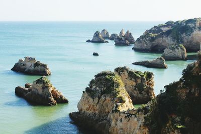 Scenic view of cliff by sea against clear sky