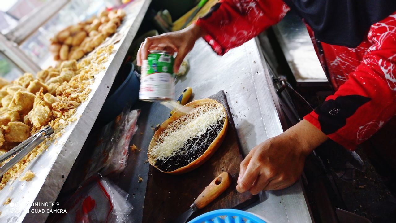 HIGH ANGLE VIEW OF MAN PREPARING FOOD AT MARKET