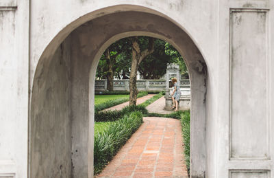 Woman sitting in park seen through arch