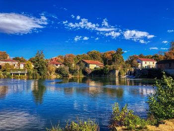 Scenic view of lake by buildings against blue sky