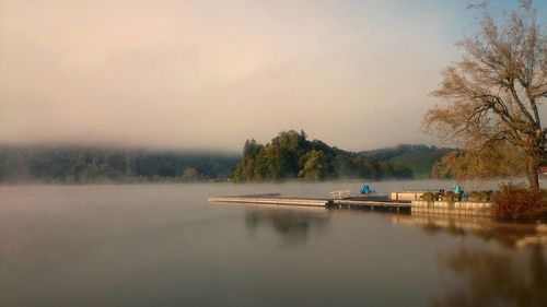 Jetty in calm lake against sky