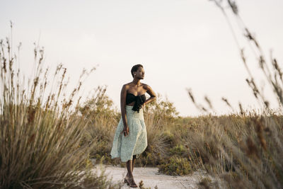 Young woman standing at field during sunset