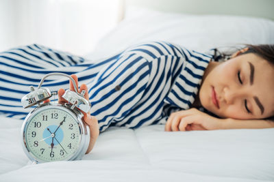 Woman sleeping with clock on bed at home