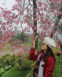 Woman standing by cherry blossom
