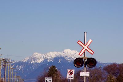 Road sign against clear blue sky during winter