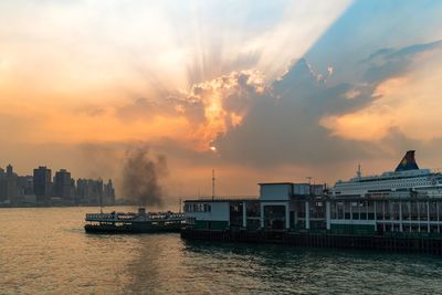 Scenic view of sea by buildings against sky during sunset