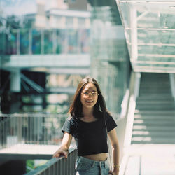 Portrait of beautiful young woman standing against railing