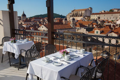 Empty chairs and tables against buildings in city