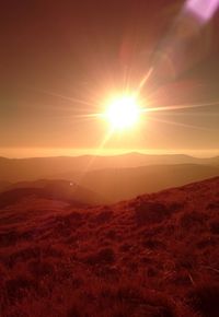 Sun shining through clouds over mountains