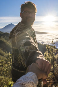 Side view of man looking at mountain against sky during sunset