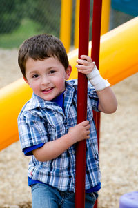 Young boy with a bandaged hand on a colorful playground