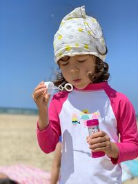 Portrait of cute girl making bubbles on the beach