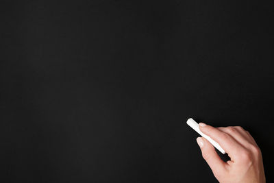 Hand holding cigarette against black background