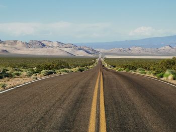 Road leading towards mountains against sky