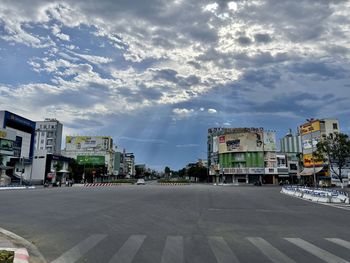 Road by buildings against sky in city