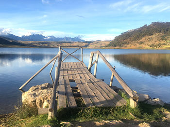 Wooden posts in lake against sky