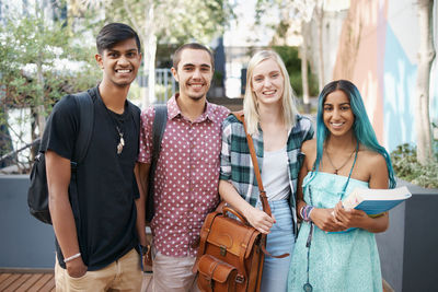 Portrait of smiling friends standing against trees