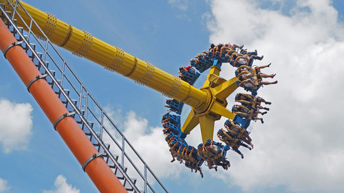 Low angle view of people enjoying amusement park ride against sky