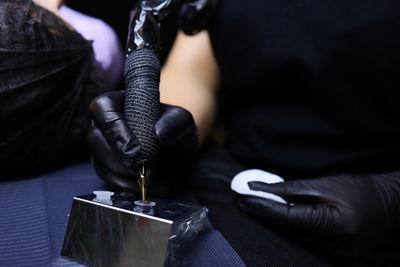 Midsection of tattoo artist holding tattoo machine