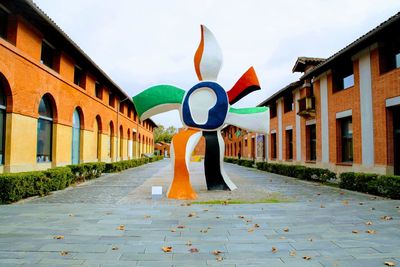 Sculpture on footpath amidst buildings in city