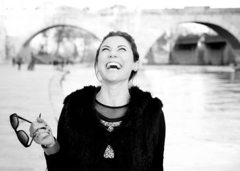 Woman laughing while standing against lake